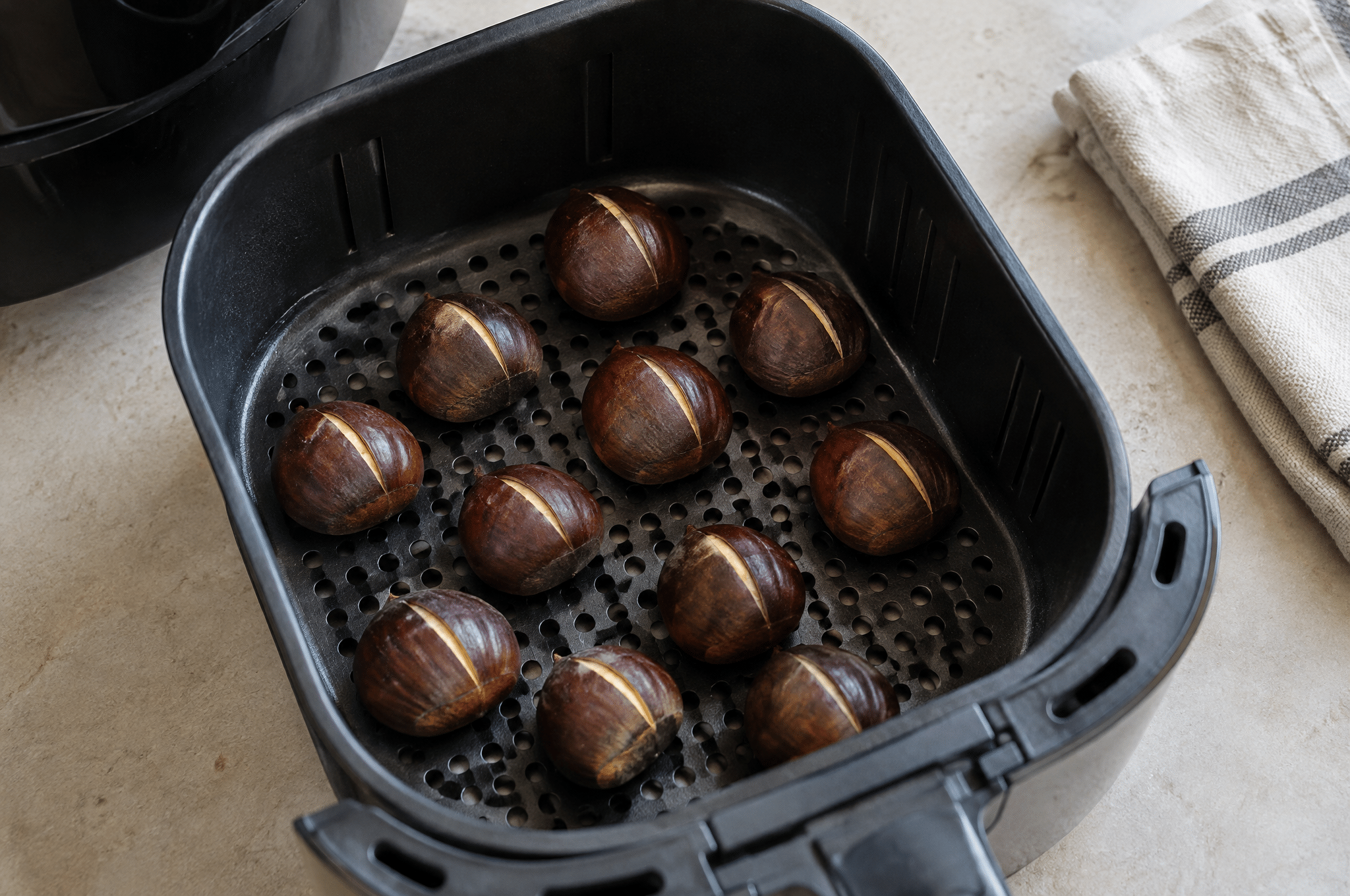 Castagne crude incise e disposte nel cestello della friggitrice ad aria